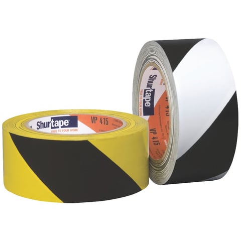 Two rolls of Shurtape safety warning tape with yellow-and-black and white-and-black diagonal stripe patterns