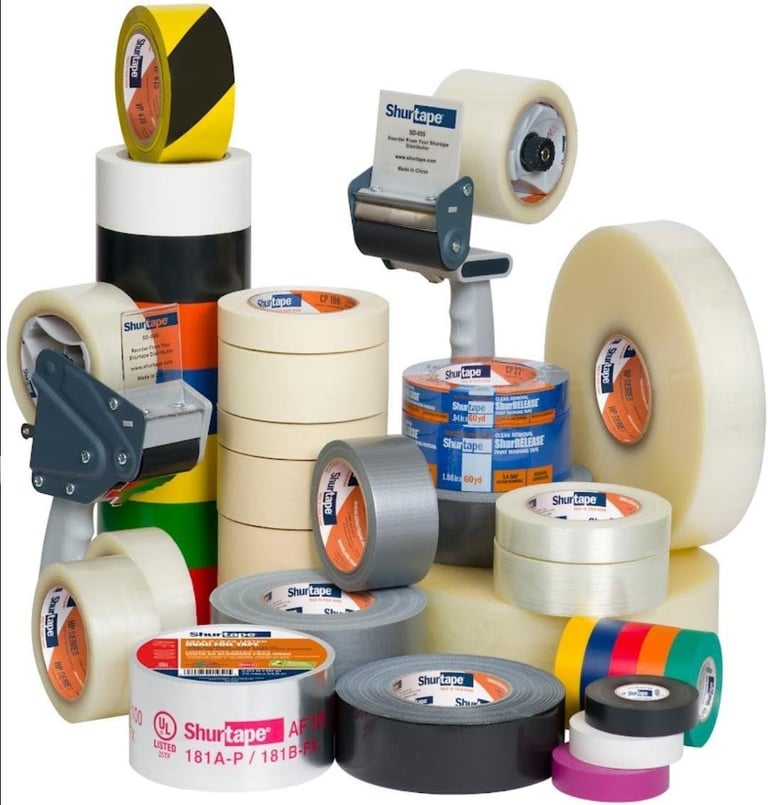 Collection of Shurtape packaging tape rolls and dispensers in various colors and sizes arranged on white background